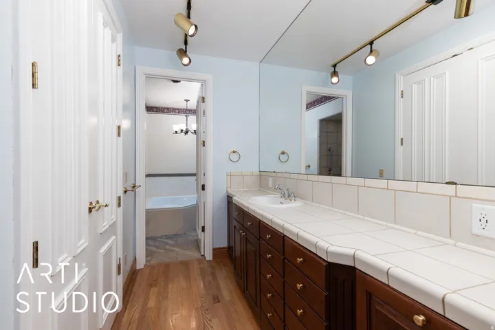 Bathroom with a tub to relax in, light wood-style flooring, vanity, and rail lighting