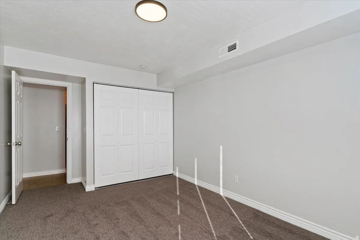 Unfurnished bedroom featuring a closet and dark colored carpet