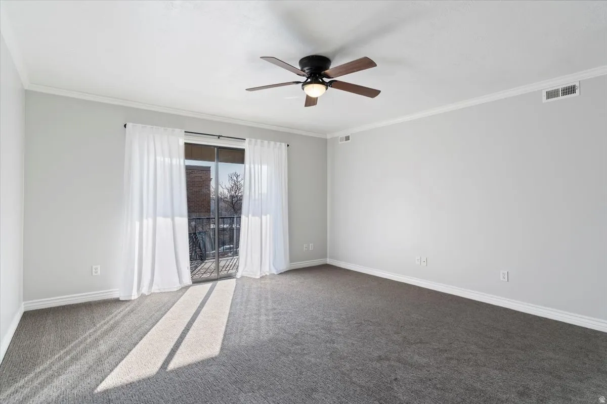 Carpeted spare room with ornamental molding and ceiling fan