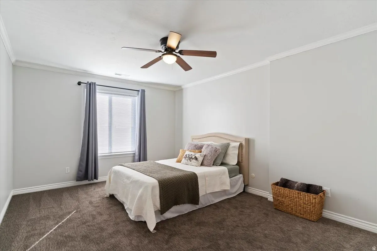 Bedroom with ornamental molding, a ceiling fan, and carpet flooring