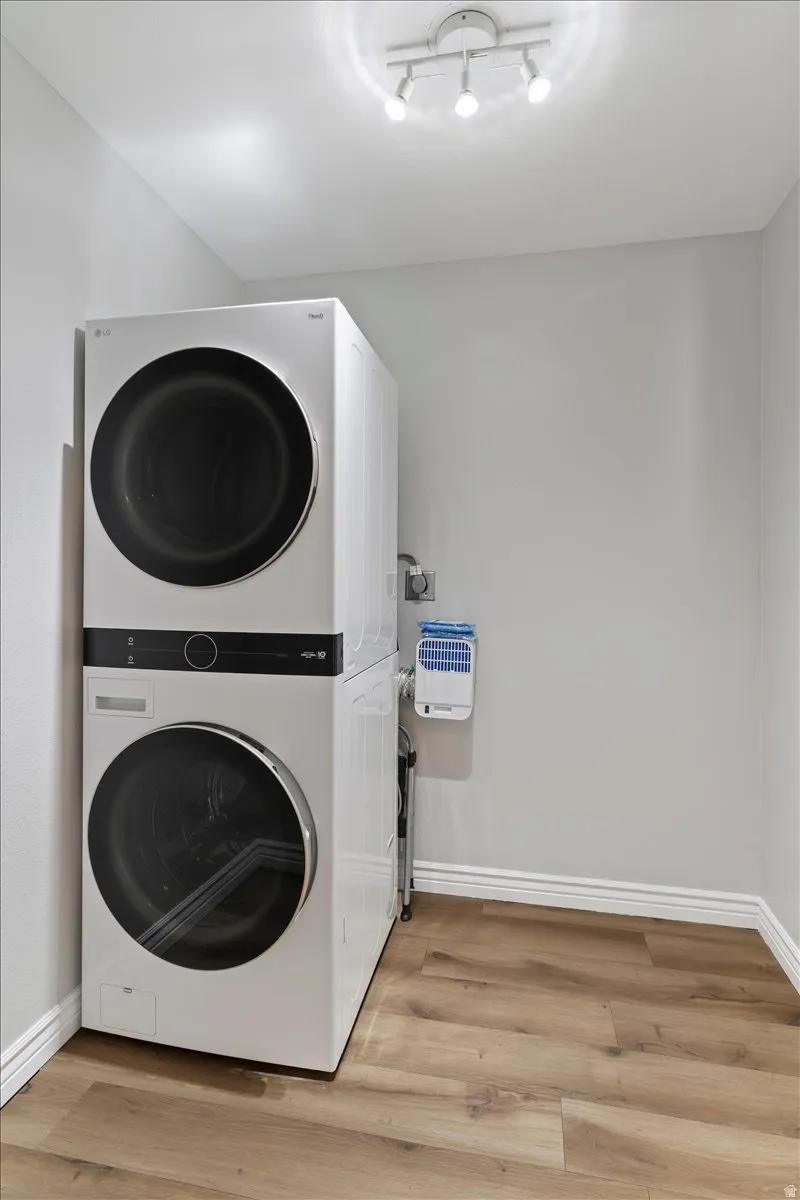 Washroom featuring stacked washer / dryer and light wood-style floors