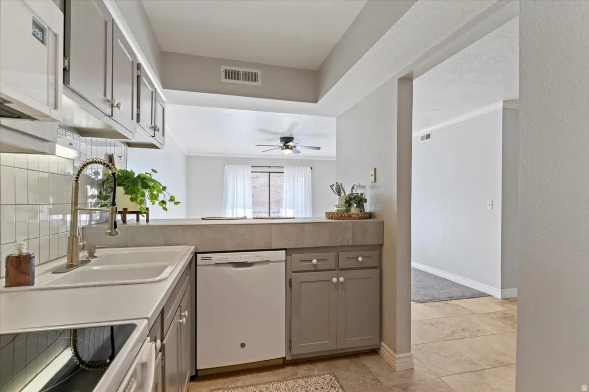 Kitchen featuring gray cabinets, white appliances, light countertops, a textured wall, and a ceiling fan