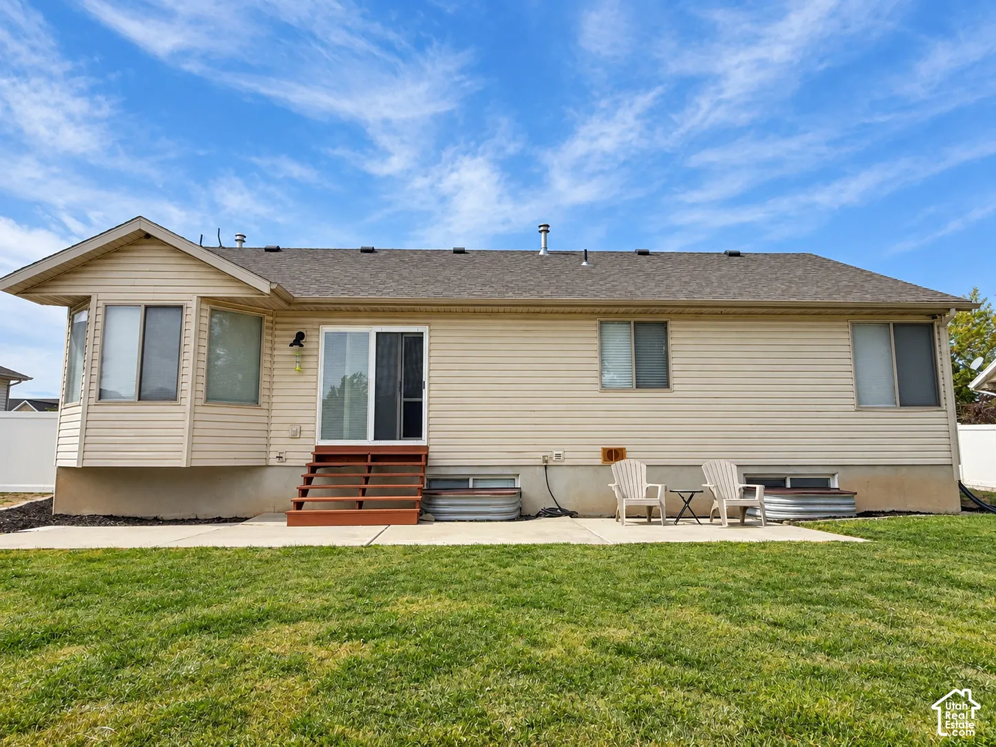 Expansive lawn with a concrete patio, wood steps, and a sliding glass door