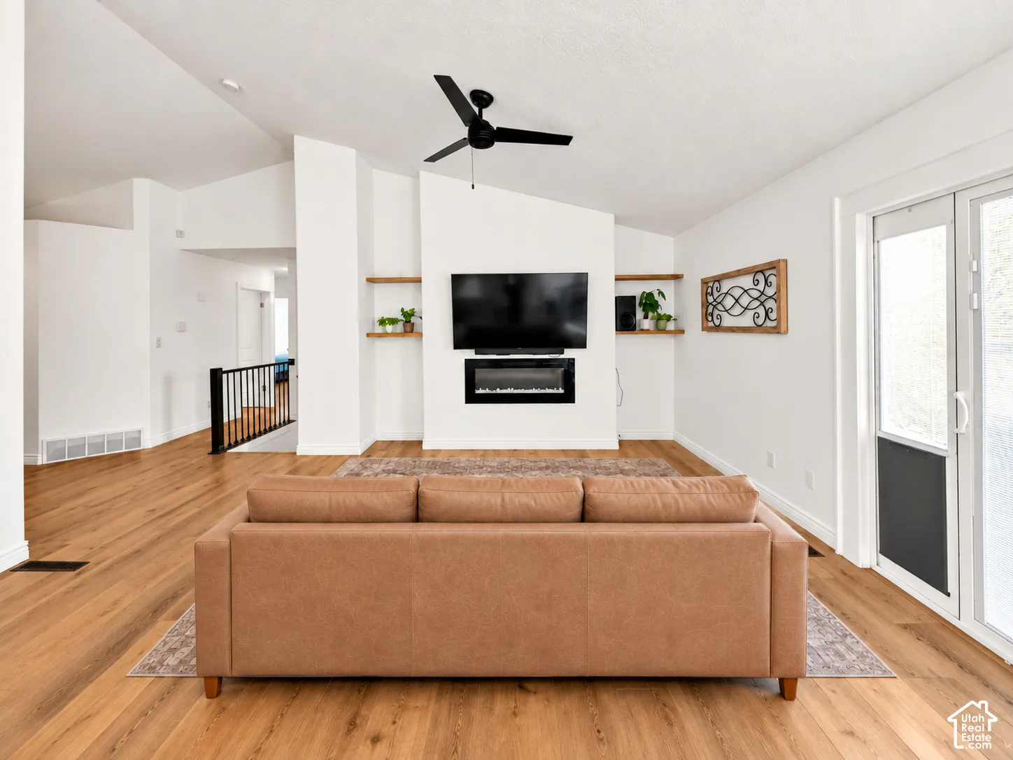 Vaulted ceilings, wood-finish flooring, built-in electric fireplace, recessed lighting, and a black ceiling fan
