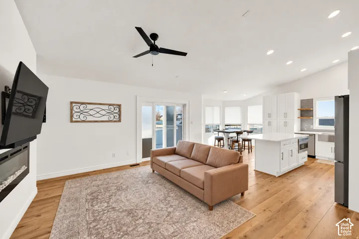 Open-concept living area with wood-finish flooring, a contemporary ceiling fan, and recessed lighting