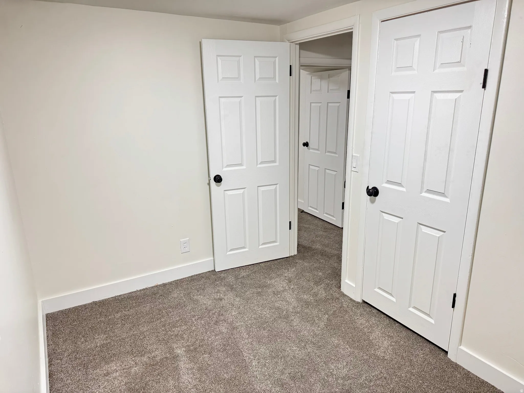 Unfurnished bedroom with dark carpet and baseboards