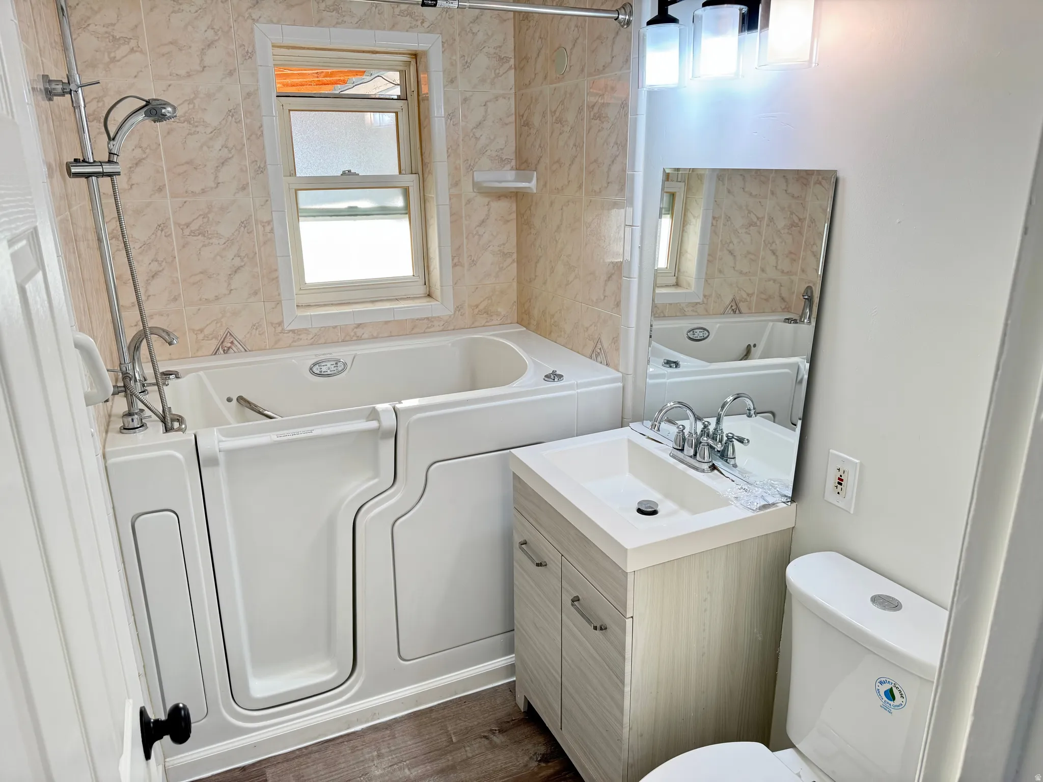 Bathroom with vanity, plenty of natural light, dark wood-type flooring, and shower / bathtub combination