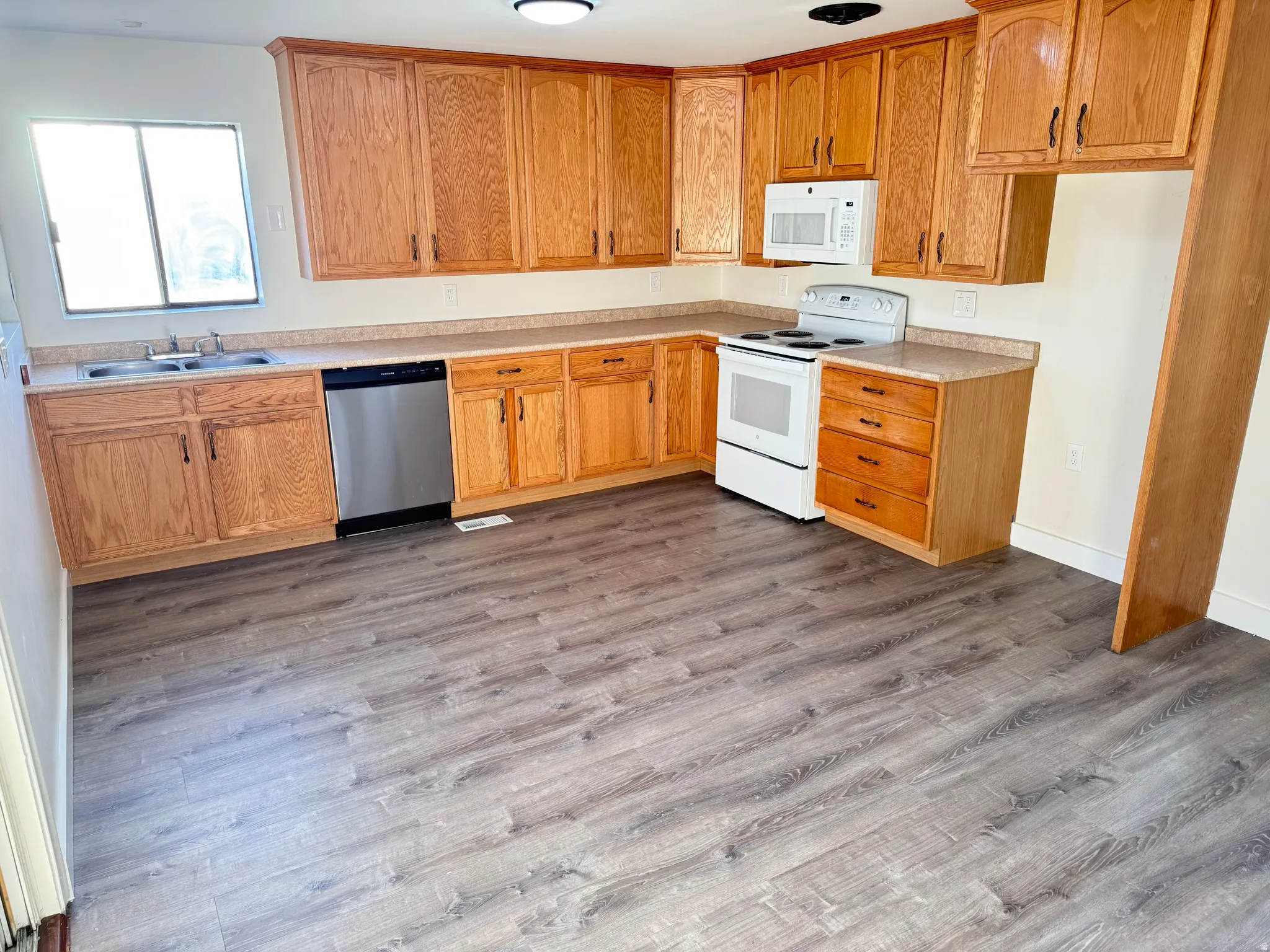 Kitchen featuring white appliances, light countertops, and dark wood-style floors