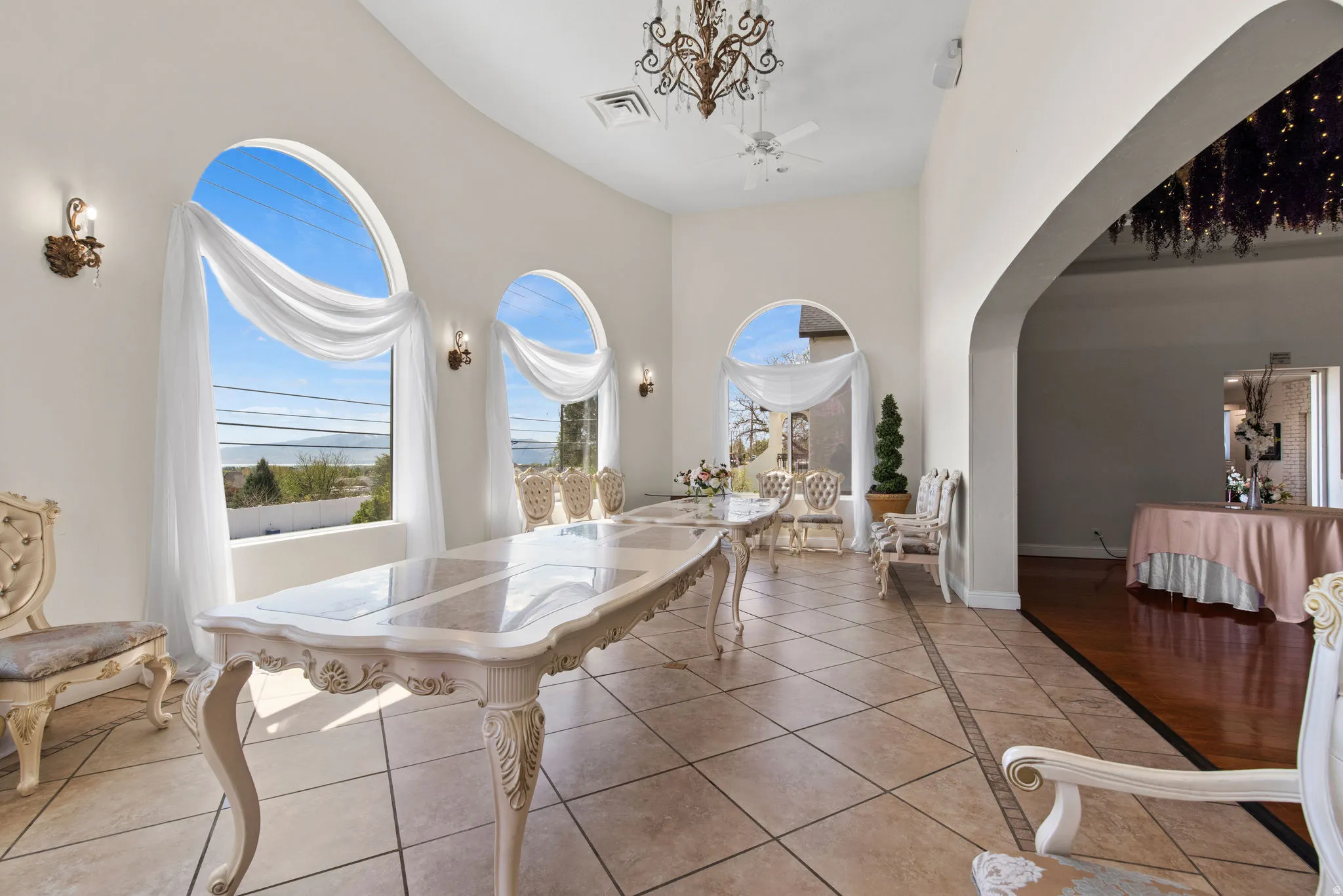 Dining space with tile patterned floors, a towering ceiling, a chandelier, and arched walkways