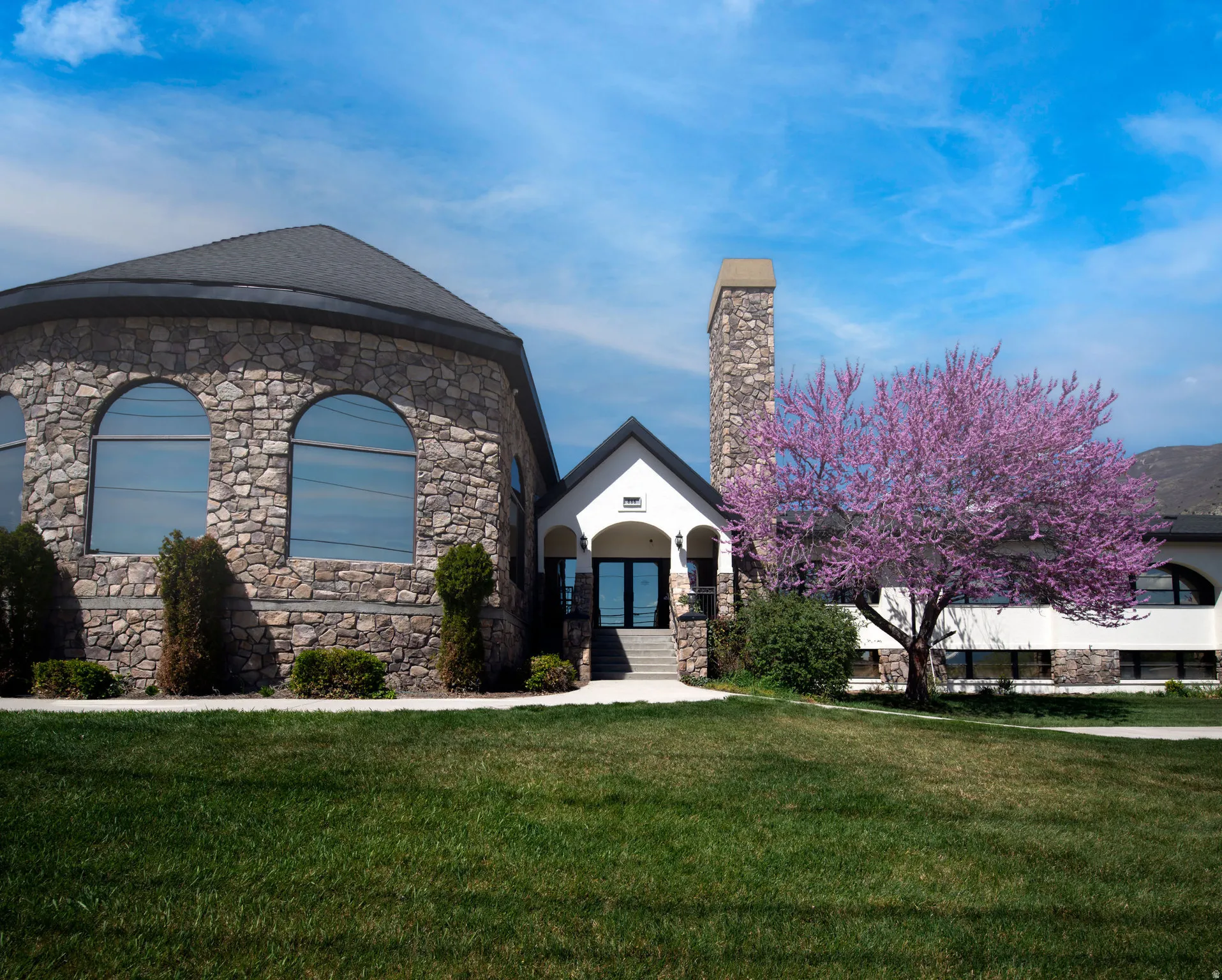 View of front facade featuring a front lawn and stone siding
