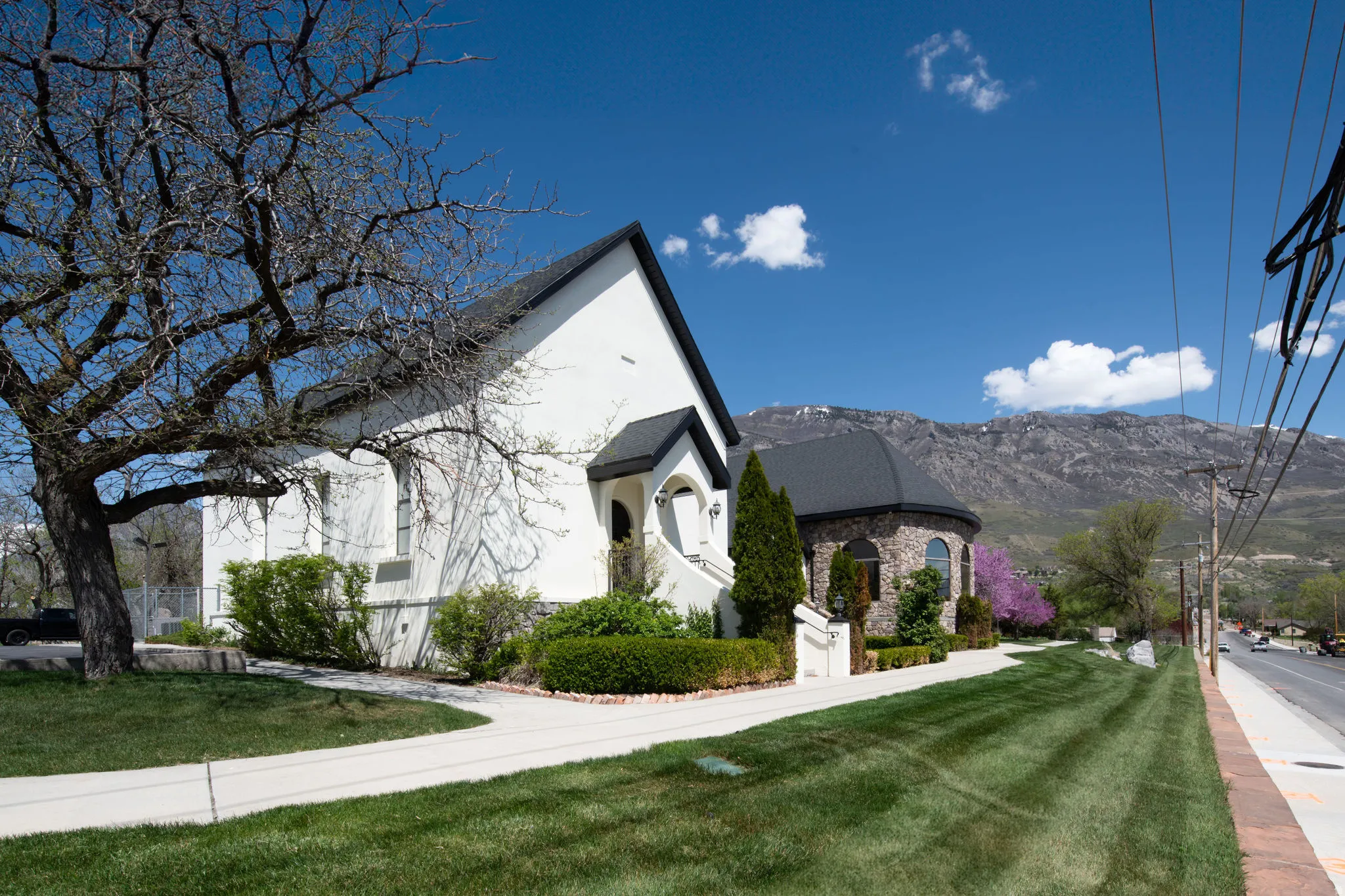 View of front of house with stucco siding, a front yard, a mountain view, and stone siding