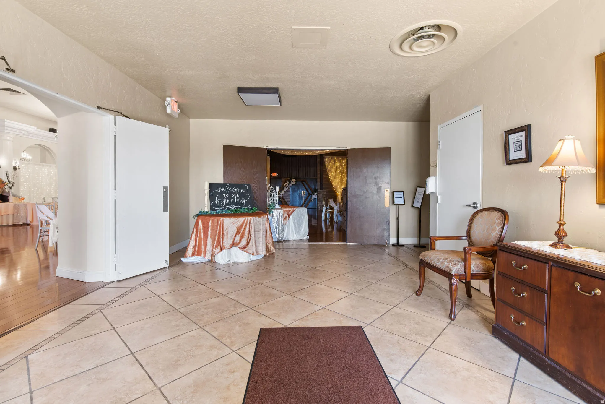 Hall with arched walkways, a textured ceiling, and light tile patterned flooring