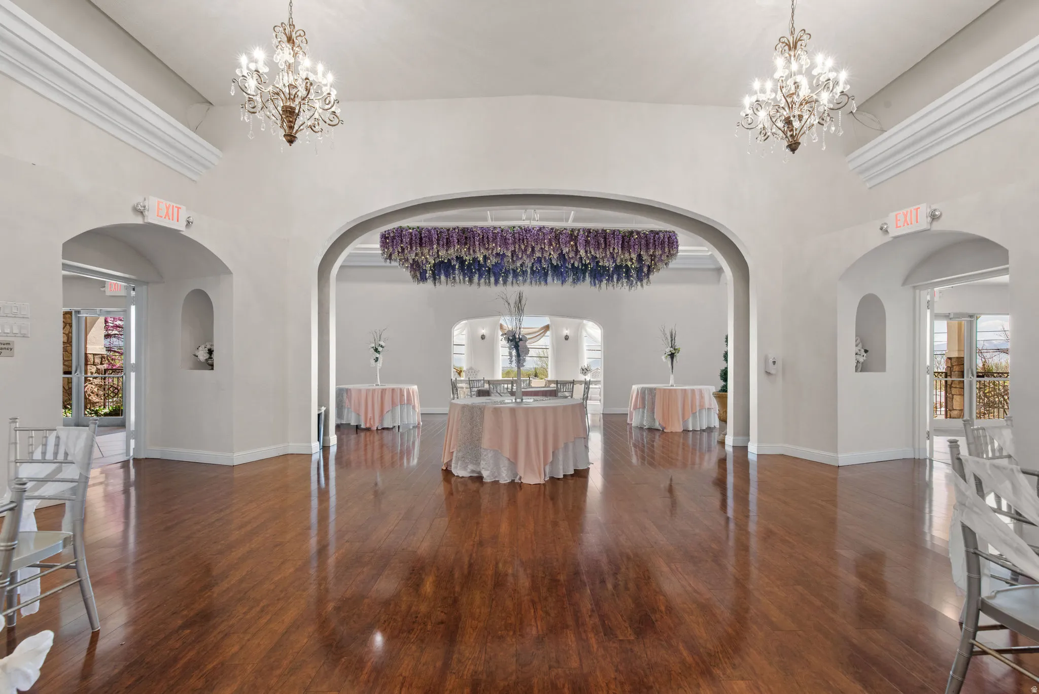 Foyer with a chandelier, arched walkways, high vaulted ceiling, and dark wood-style flooring