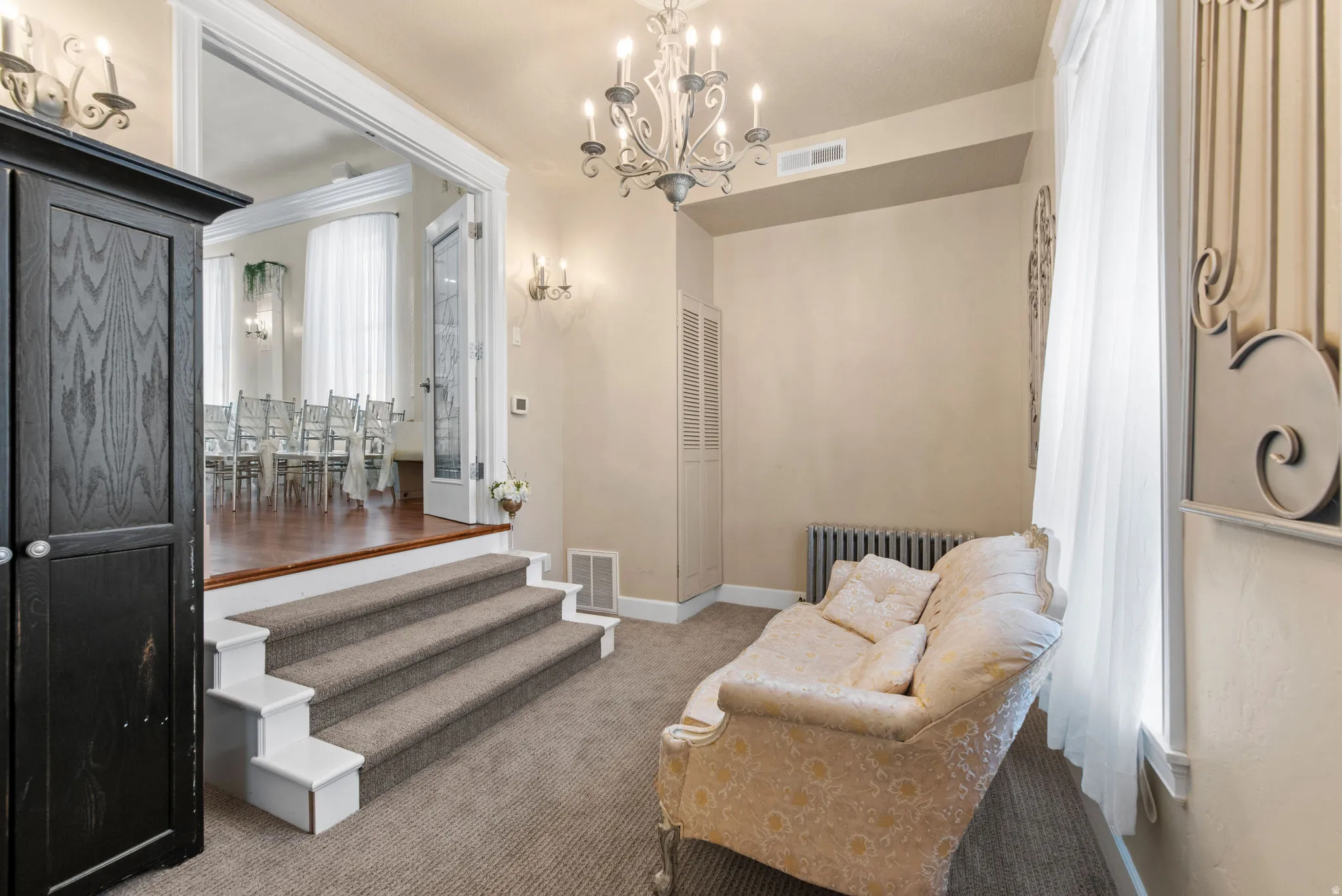 Living area featuring radiator, a chandelier, and carpet