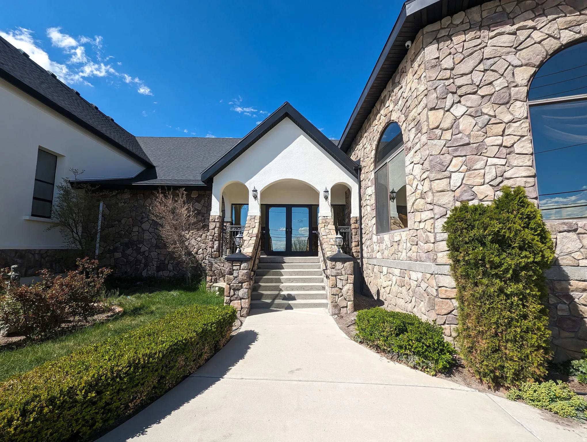 Property entrance featuring stone siding, french doors, covered porch, and stucco siding