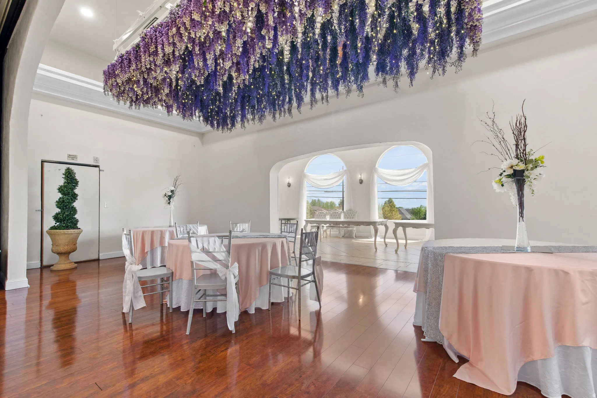Dining area featuring hardwood / wood-style flooring, arched walkways, and a towering ceiling