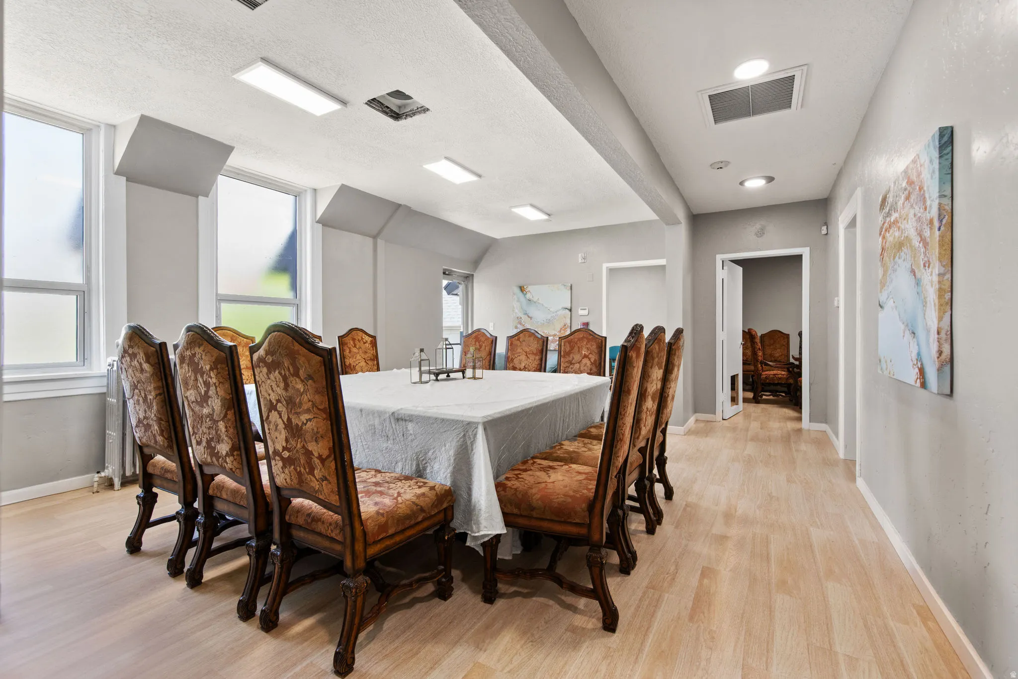 Dining room with a textured ceiling, light wood-style flooring, and radiator heating unit