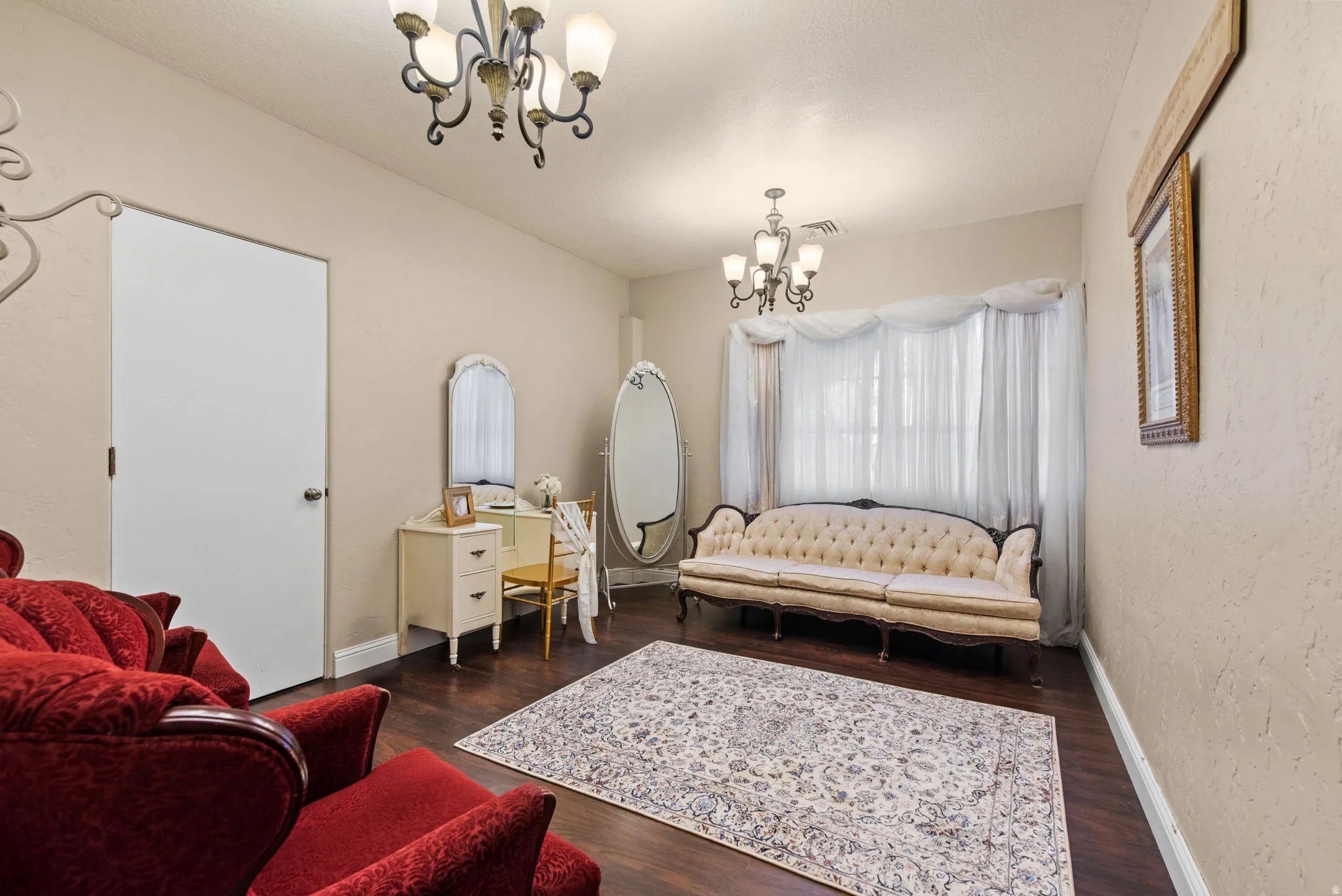 Sitting room featuring a chandelier, a textured wall, and dark wood finished floors