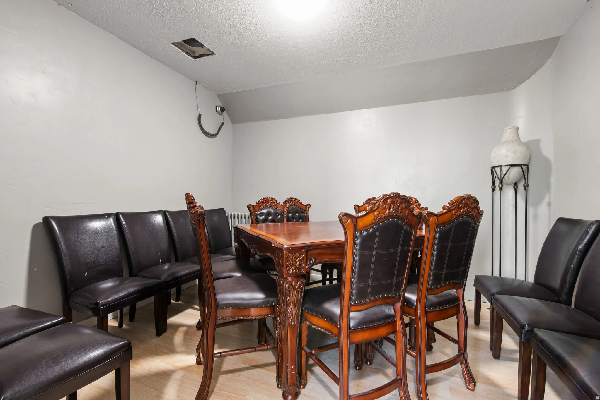 Dining room featuring a textured ceiling, light wood-style flooring, and vaulted ceiling