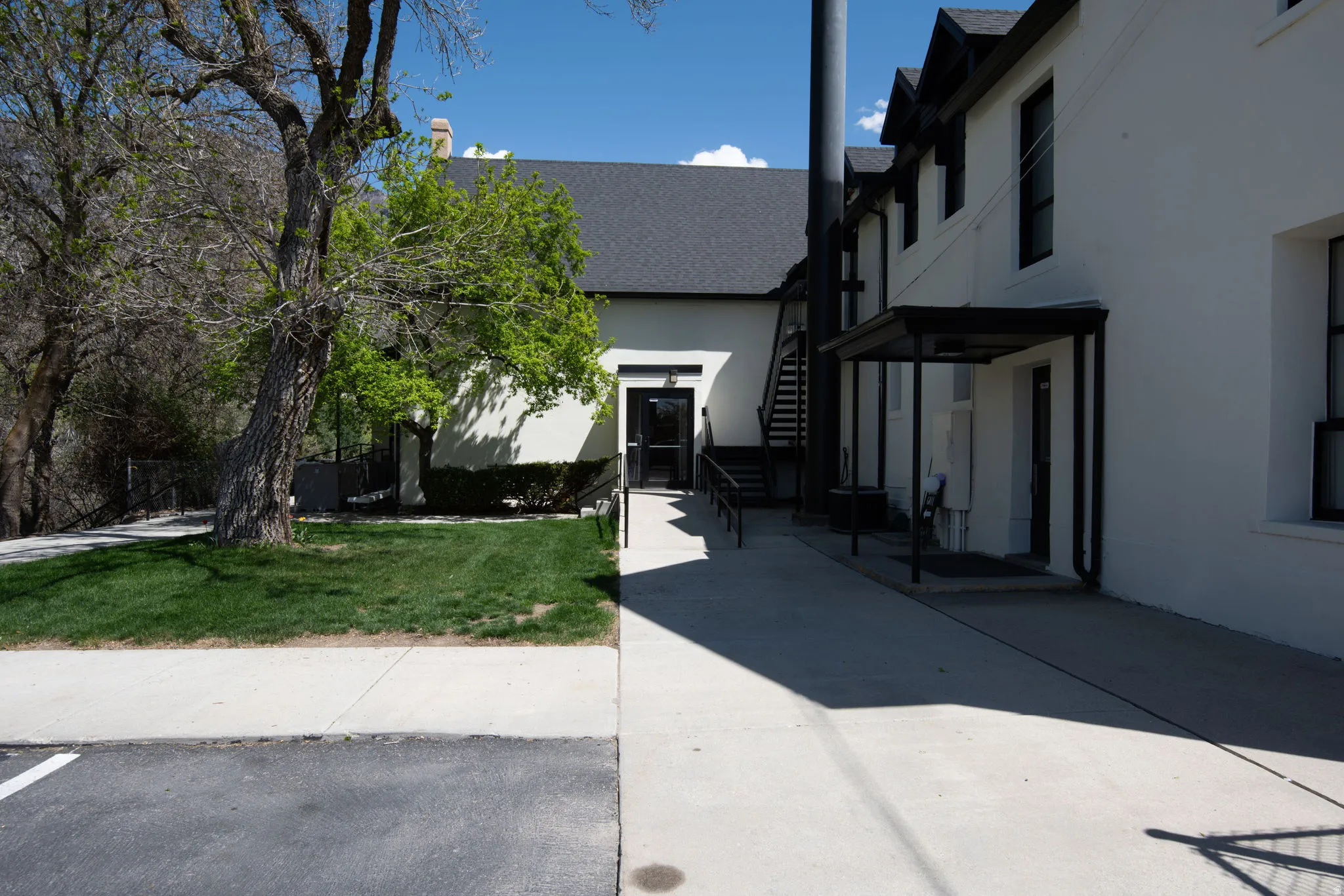 Exterior space with a front lawn, stucco siding, roof with shingles, a patio, and stairway