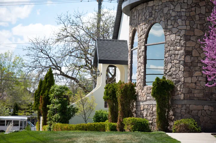 View of property exterior featuring stone siding, stucco siding, and a yard