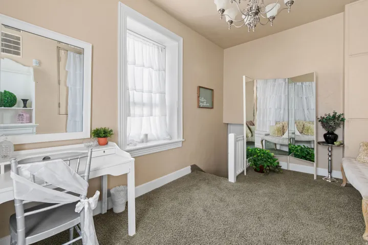 Carpeted office space featuring a chandelier and baseboards