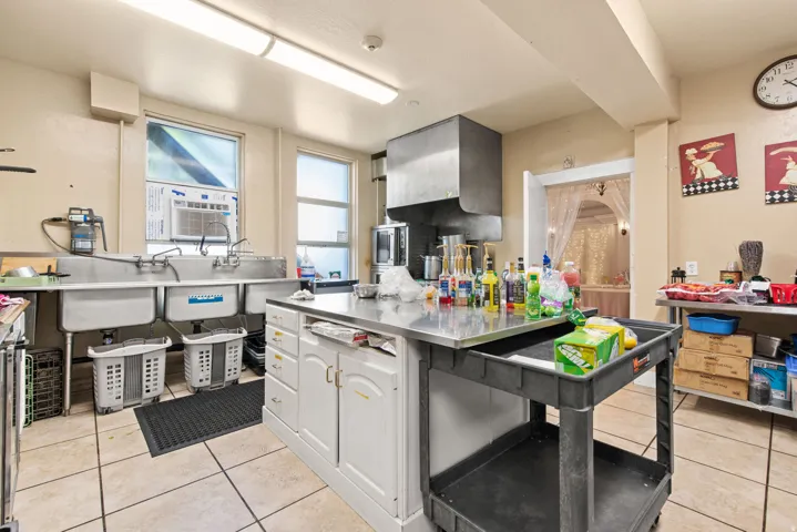 Kitchen with stainless steel counters, light tile patterned flooring, and white cabinets