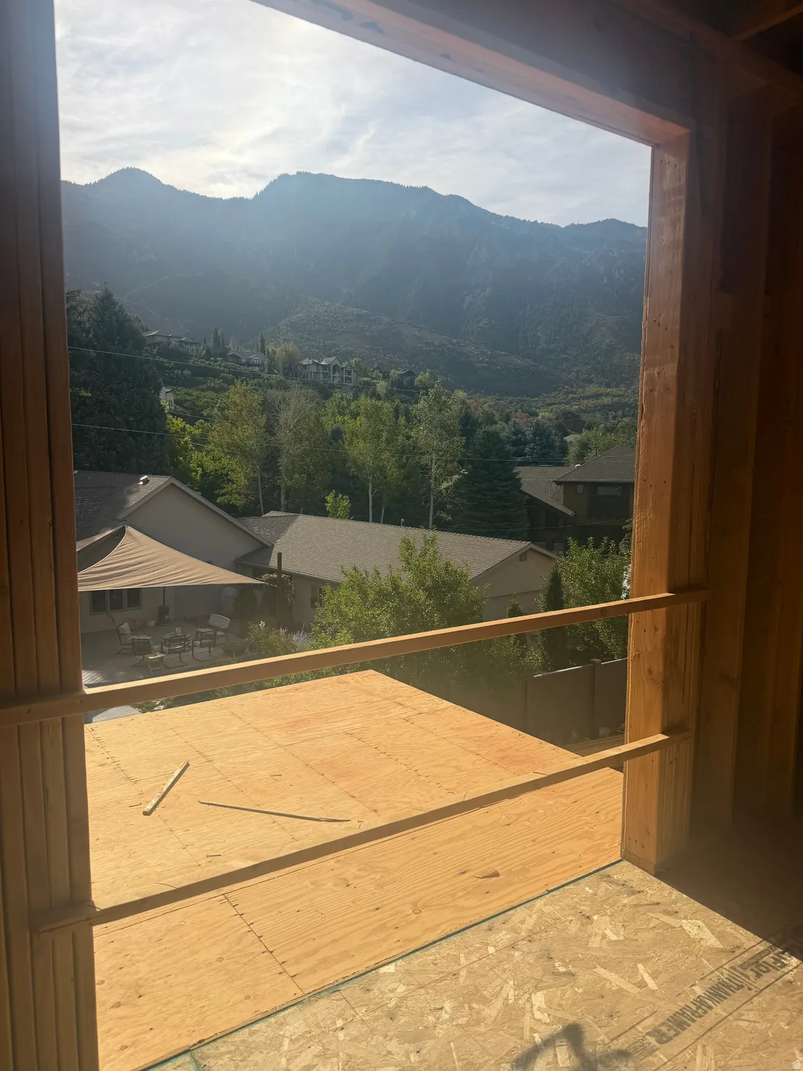Expansive elevated deck with wood-finish flooring and horizontal metal railings, framed by mountain vistas and verdant valley landscape