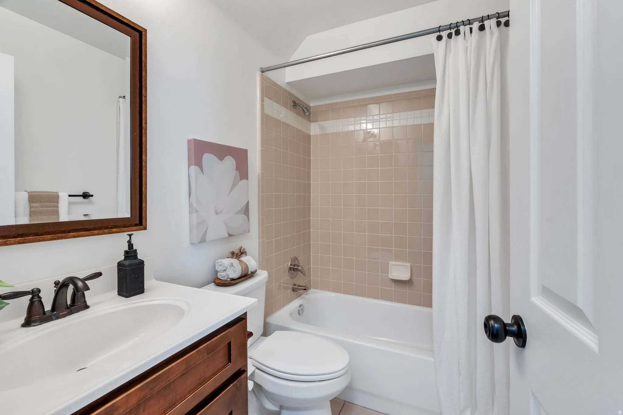 Bathroom featuring a white vanity with integrated sink, dark wood-finish cabinetry, and a bronze-finish faucet