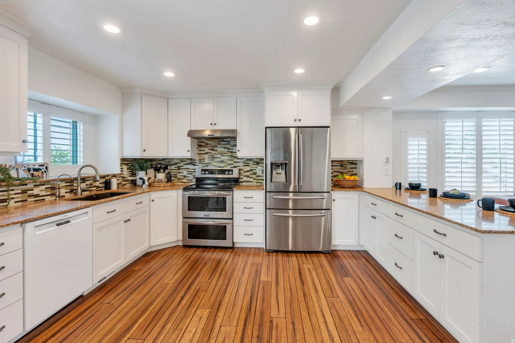 Kitchen featuring wood-finish flooring, white cabinetry, stainless steel appliances, and light-toned countertops
