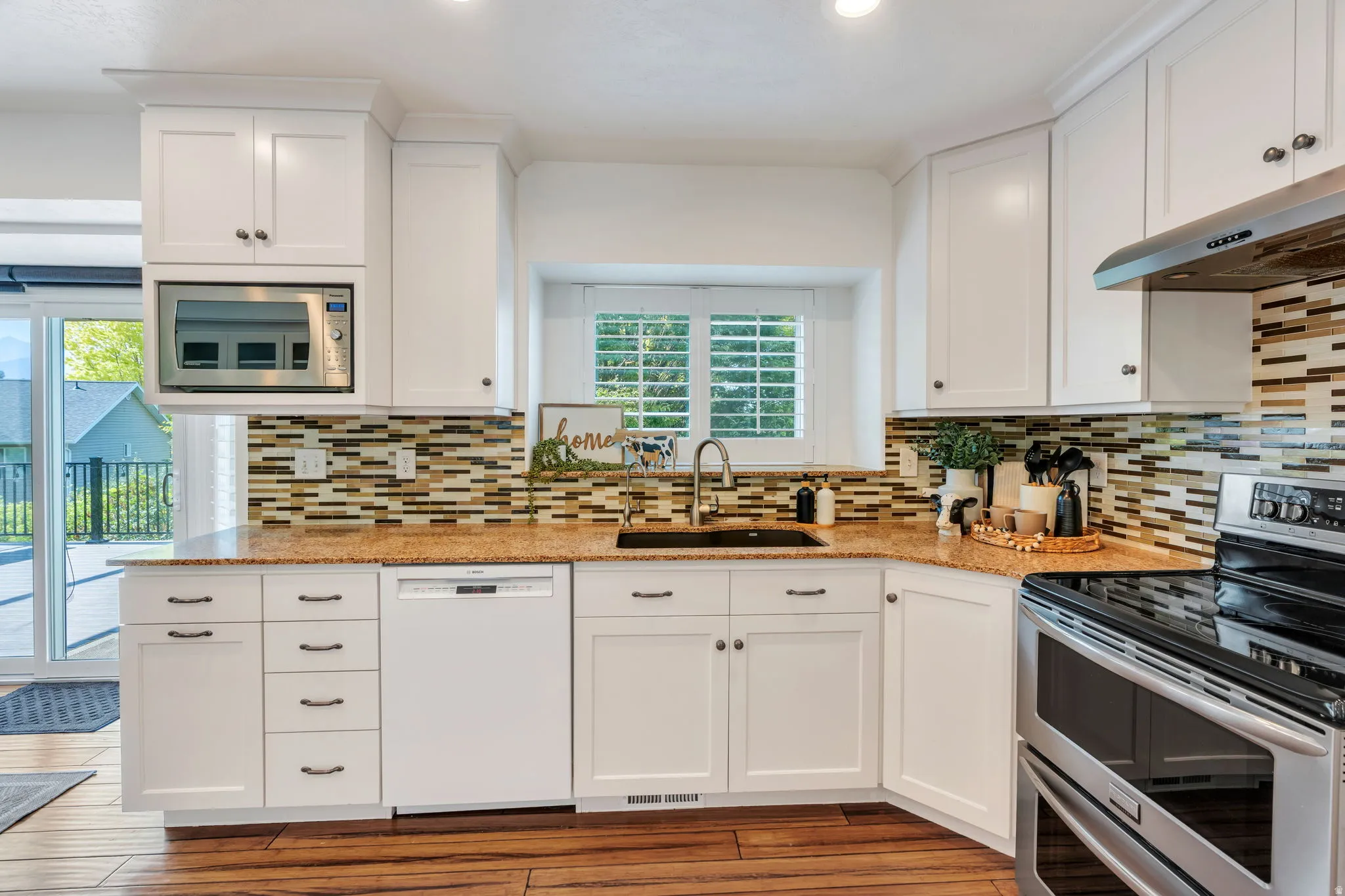 Kitchen featuring white shaker-style cabinetry, granite countertops, and a mosaic tile backsplash