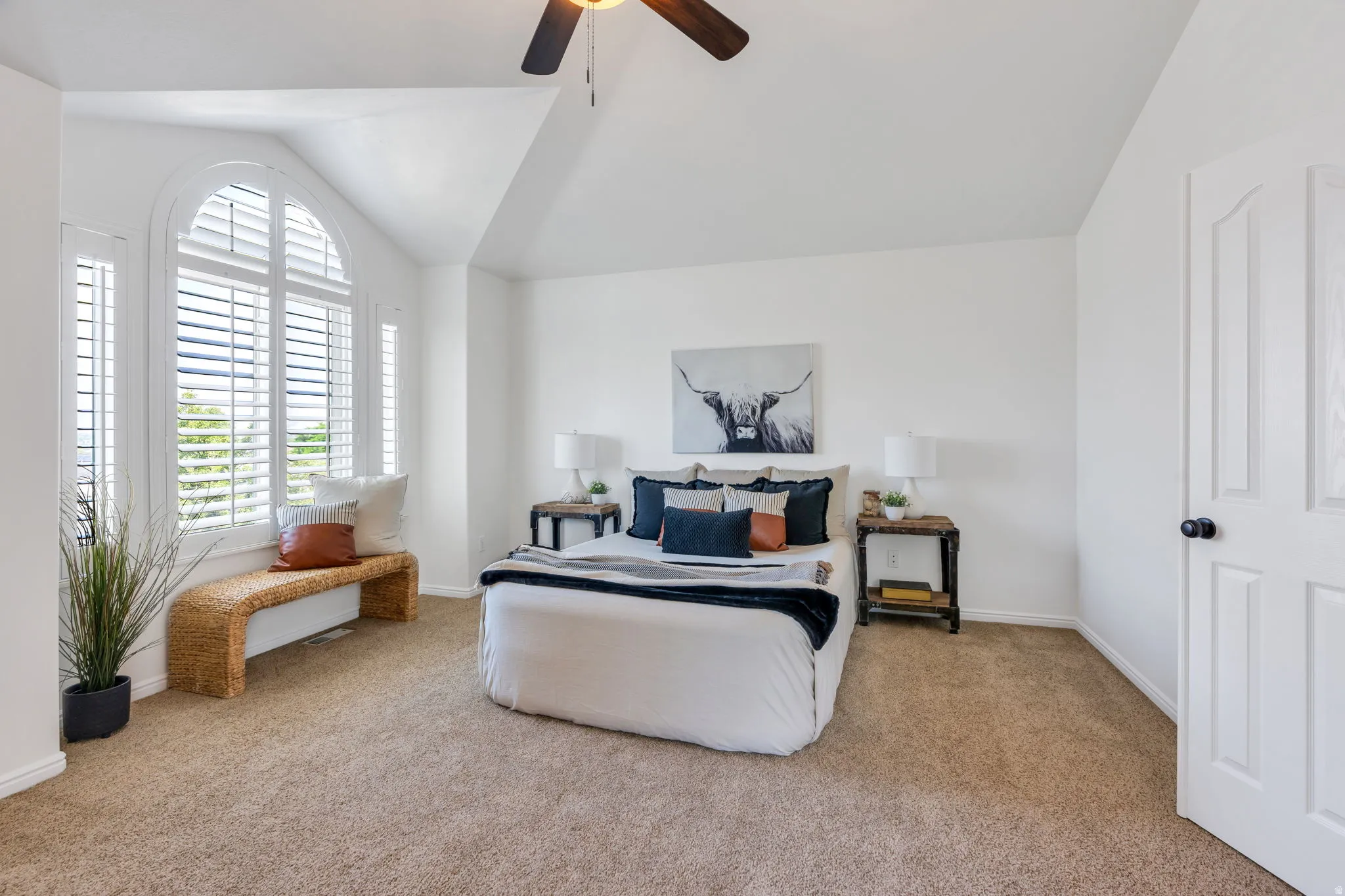 Large primary suite with view windows, plantation shutters and vaulted ceiling with ceiling fan