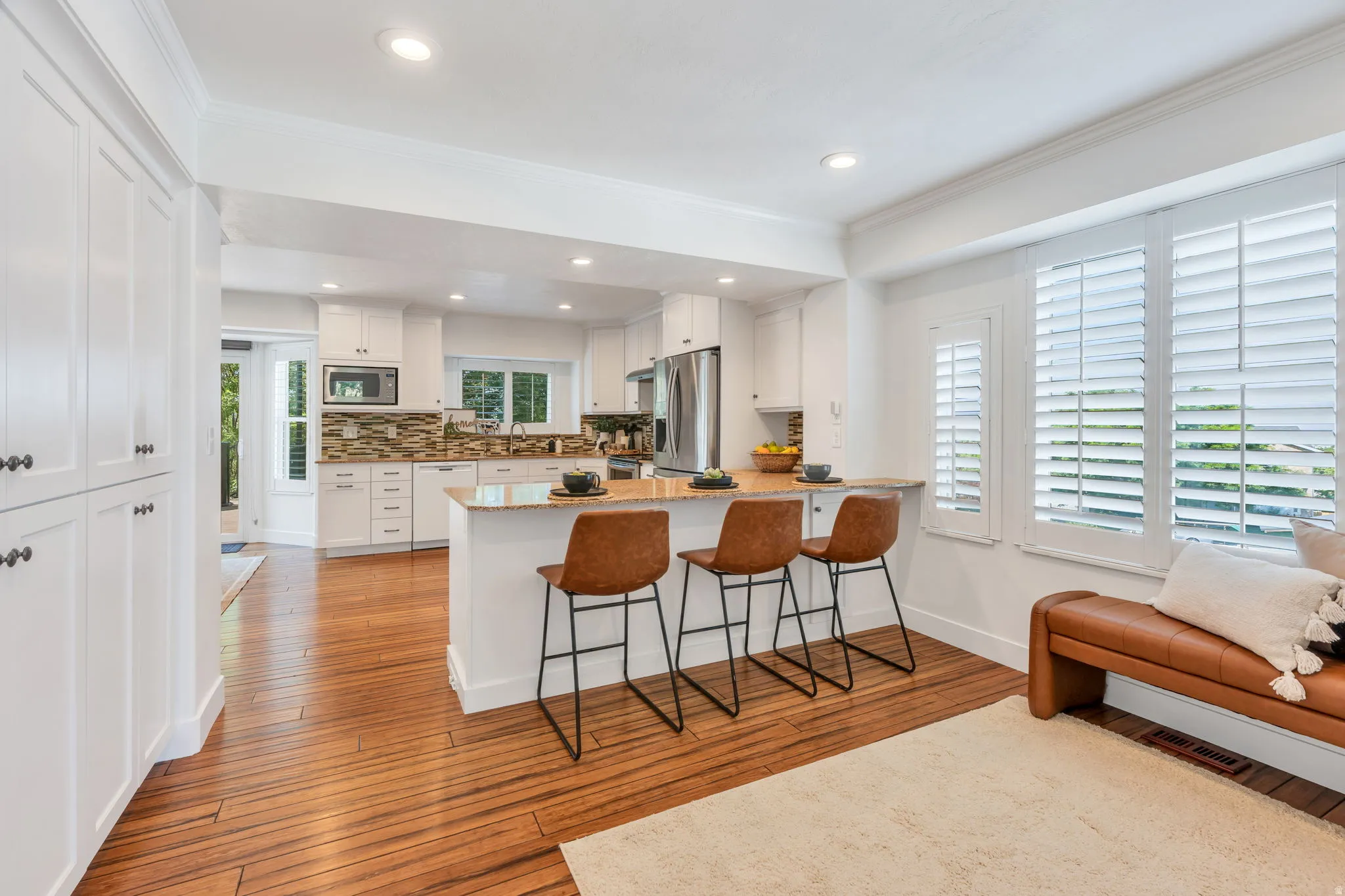 Kitchen with bamboo flooring, white cabinetry, a granite-style countertop peninsula, mosaic tile backsplash, and recessed lighting