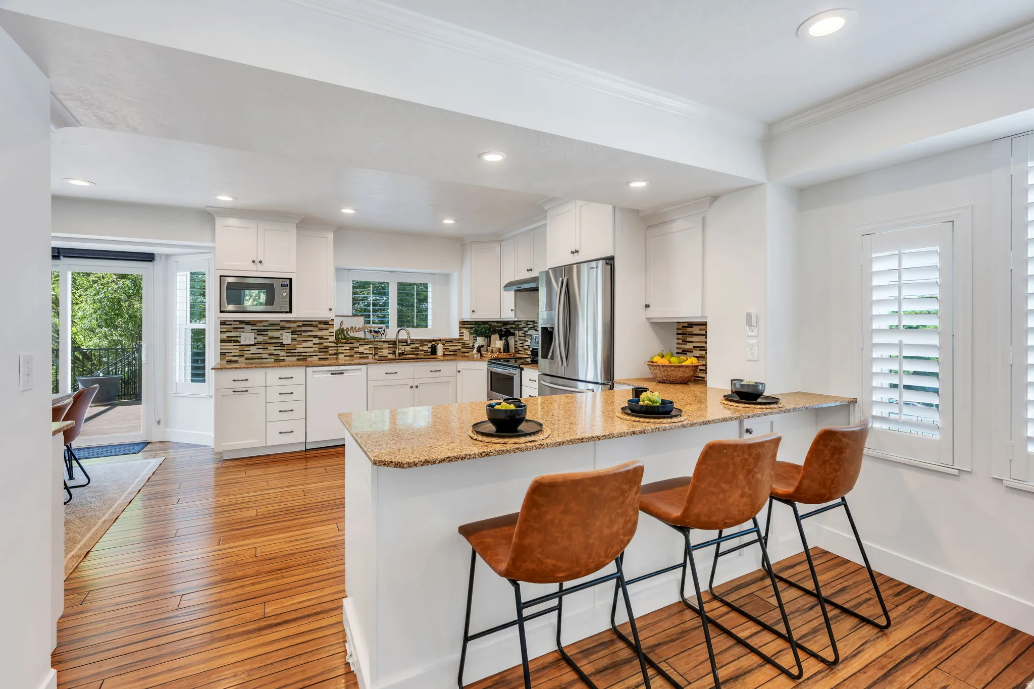 Gourmet kitchen featuring white cabinetry, stainless steel appliances, and a mosaic tile backsplash