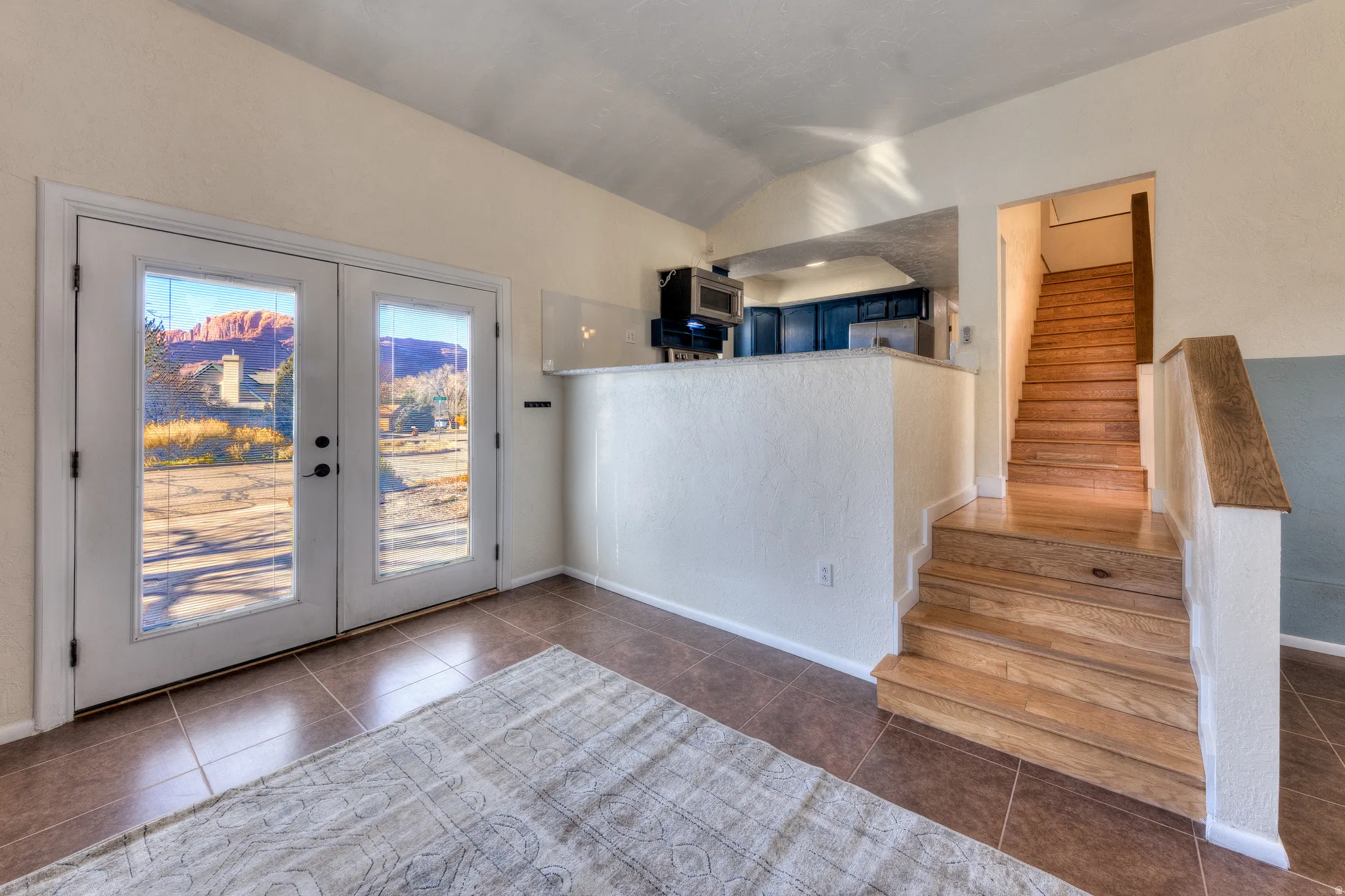 Great room with vaulted ceiling, stairs, new tile flooring, and french doors