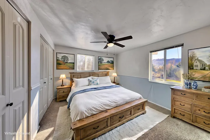 Bedroom with light carpet, a ceiling fan, and multiple closets