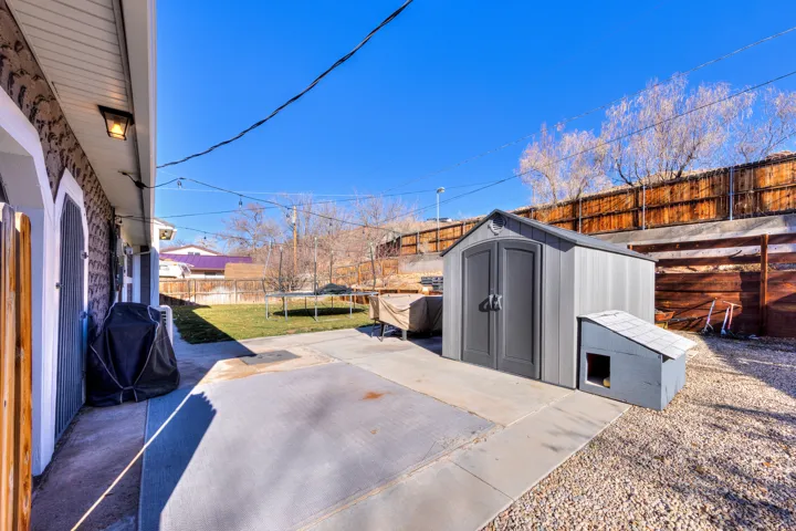 Fenced backyard featuring a patio area, grilling area, shed and terraced garden
