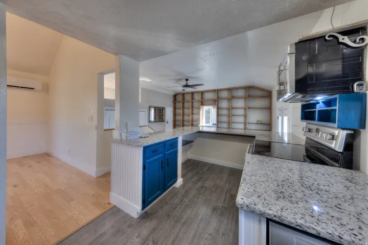 Kitchen with a peninsula, vaulted ceiling, LVP flooring, and light granite countertops