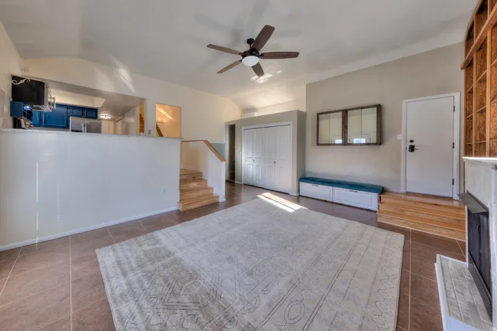 Great room with stairway, ceiling fan, lofted ceiling, and new tile flooring