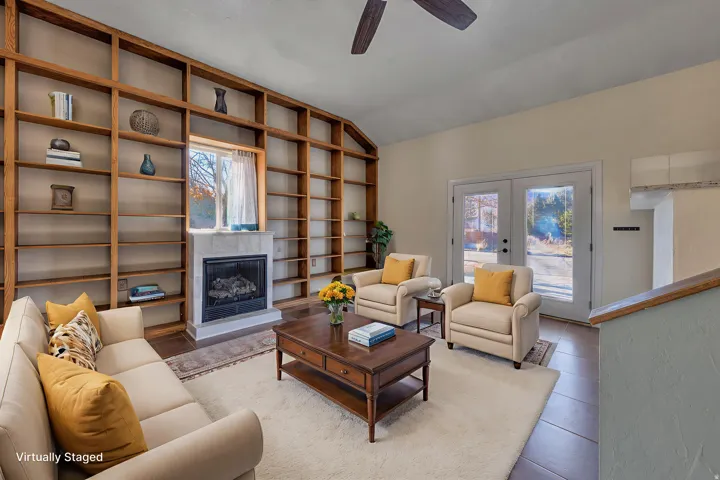 Great room with built in bookcases, beautiful natural light, a fireplace with raised hearth, new tile floors, and vaulted ceiling