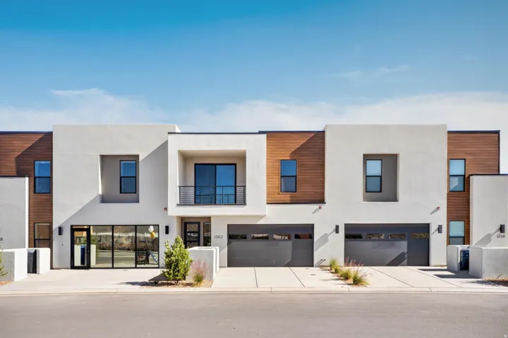 Contemporary house with a balcony, concrete driveway, stucco siding, and a garage