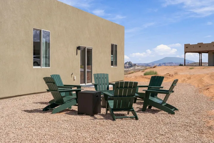 Stucco exterior, sliding glass door, fixed windows, gravel ground cover, and distant mountain scenery