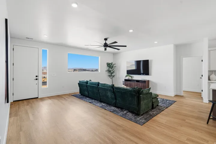 Expansive living area with wood-finish flooring, recessed lighting, and a modern ceiling fan
