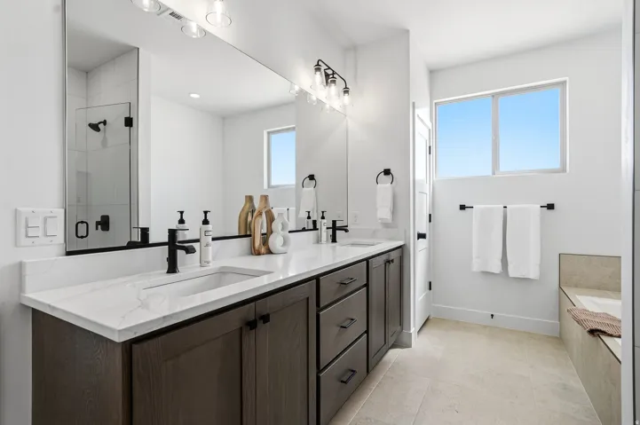 Double vanity with white countertop, dark wood-finish cabinetry, and matte black fixtures