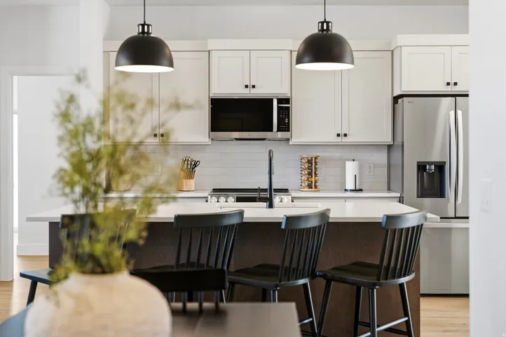 Kitchen featuring white shaker cabinetry, stainless steel appliances, a center island with seating, a subway tile backsplash, and pendant lighting