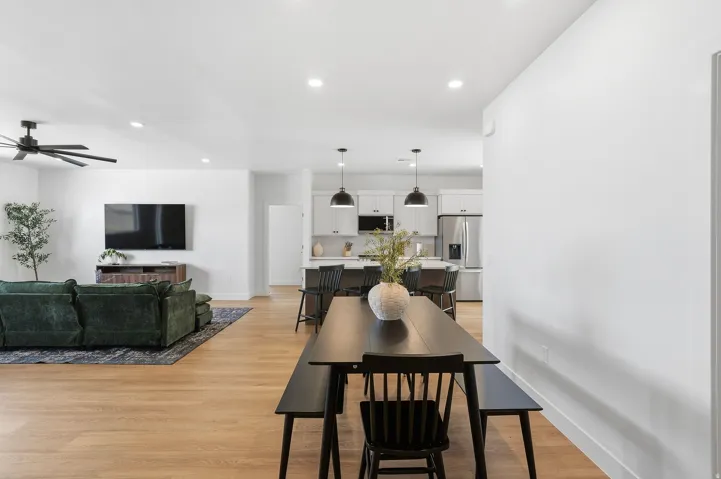 Open-concept living space featuring wood-finish flooring, recessed lighting, a modern ceiling fan, and a kitchen with pendant lighting and stainless steel appliances