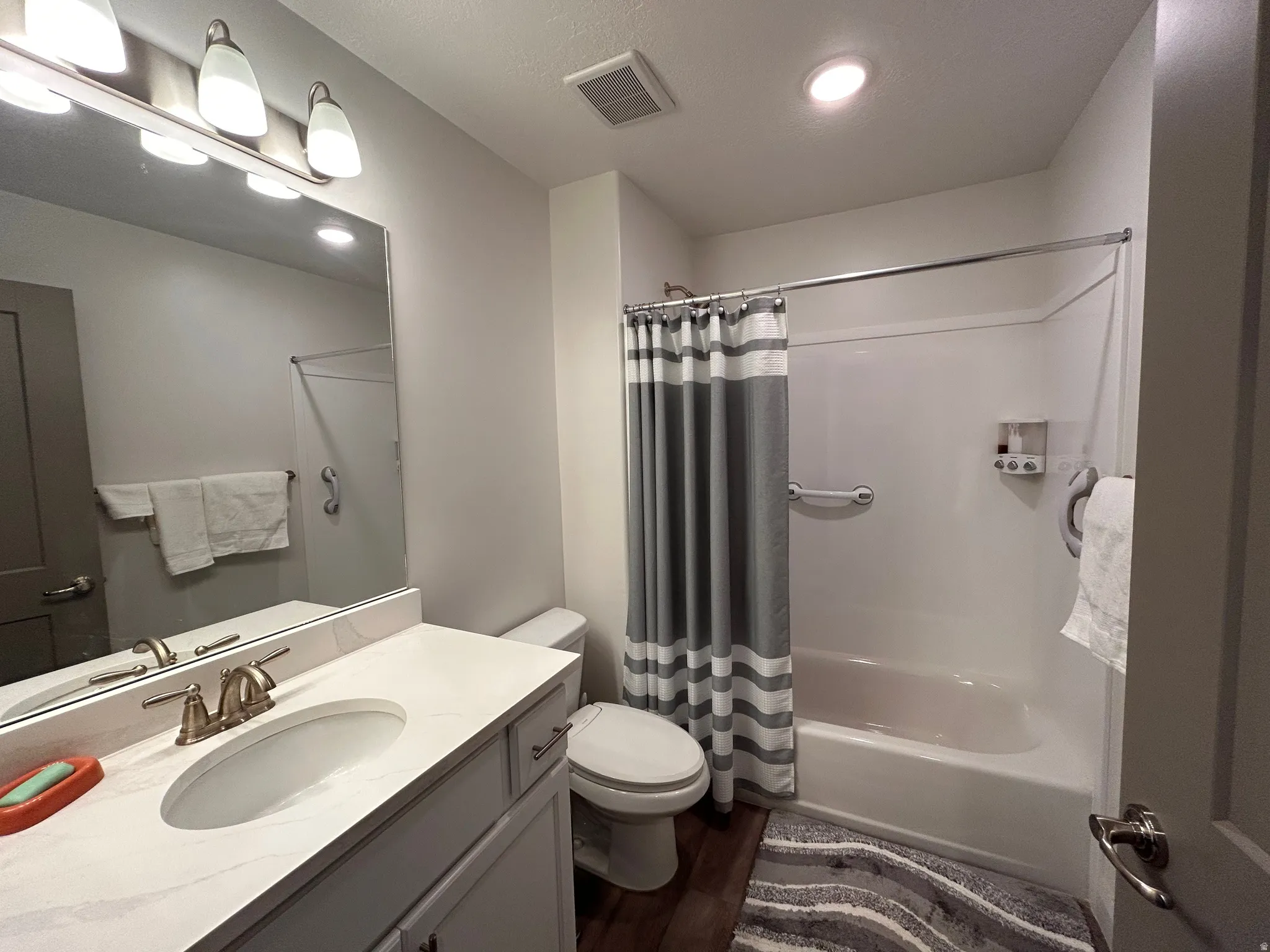 Full bathroom featuring vanity, shower / tub combo, dark wood finished floors, and recessed lighting