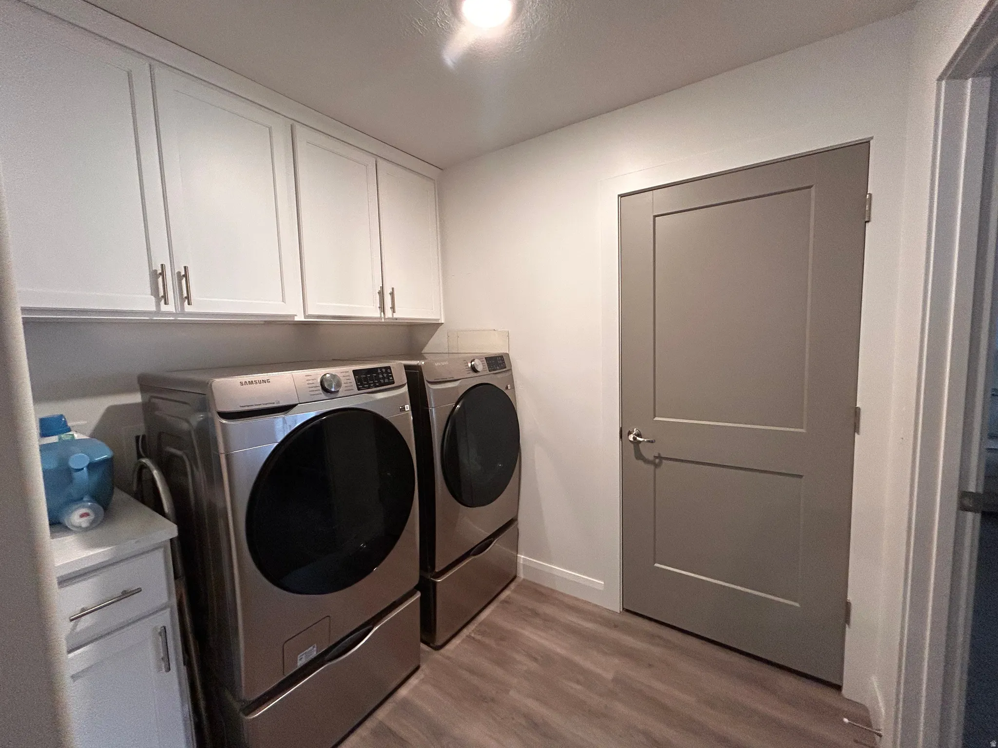 Laundry area with washer and clothes dryer, wood finished floors, and cabinet space