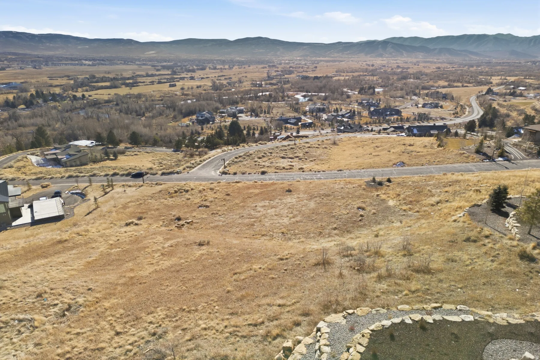 Aerial view of property and surrounding area featuring a mountainous background and nearby suburban area
