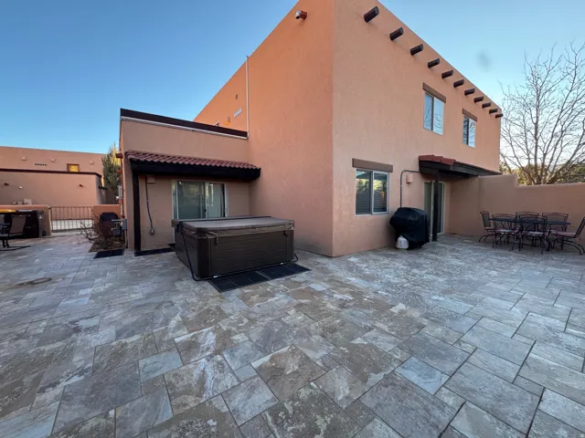 Back of house with a patio, stucco siding, outdoor dining space, a hot tub, and a tile roof